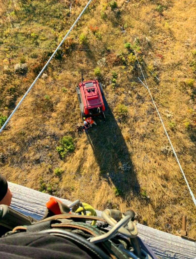 Aerial view of a red Fat Truck Wagon amphibious all-terrain vehicle pulling wire during electric utility work in autumn terrain