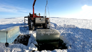 Fat Truck all-terrain vehicle with crane lifting ice blocks in arctic conditions