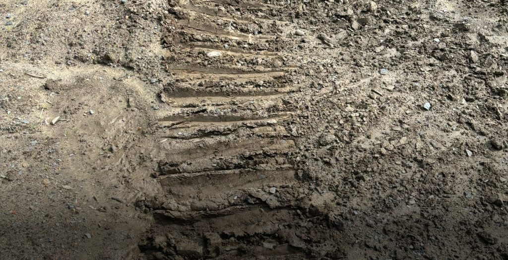 Close-up of Fat Truck oversized tire tread pattern pressed into soft mud, showing low ground pressure off-road capability