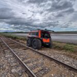 RCMP FAT TRUCK® amphibious utility vehicle navigating flood-damaged terrain alongside washed-out railway tracks in Swan River, Manitoba.