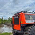 Rear view of RCMP FAT TRUCK® Search and Rescue vehicle on the bank of a fast-moving flooded river during flood relief operations in Swan River, Manitoba.